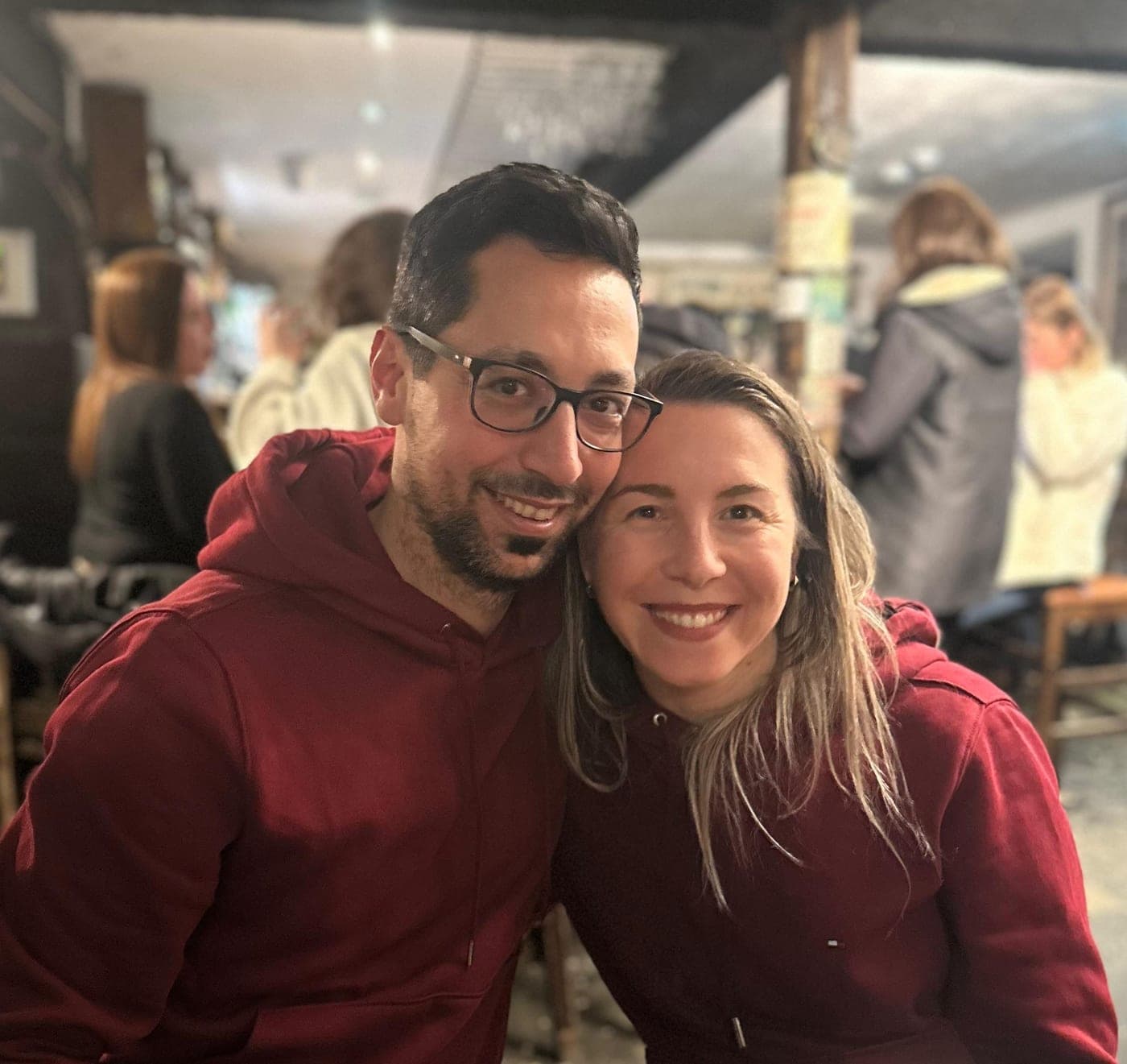 Saliha and Mustafa, cheek to cheek and smiling, in a warmly lit café
